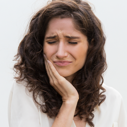 Woman in discomfort from sensitivity, holding the side of her cheek