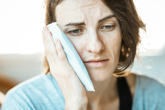 Photo of a woman holding an icepack to her jaw. Photo by Engin Akyurt on Unsplash