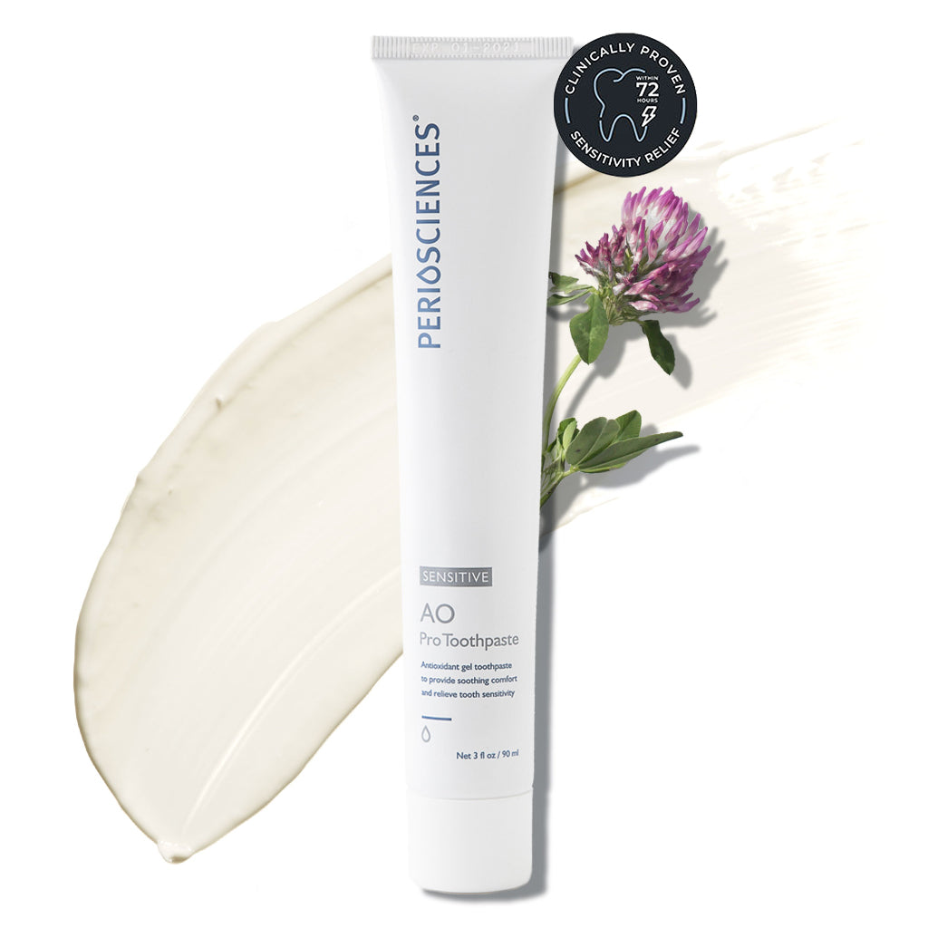 Tube of sensitive toothpaste with a smear and a flower on white background.